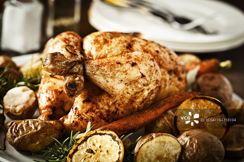 烤鸡晚餐配柠檬、土豆、胡萝卜和迷迭香图片素材