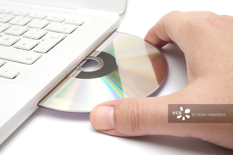 一人将CD装入白色笔记本电脑图片素材