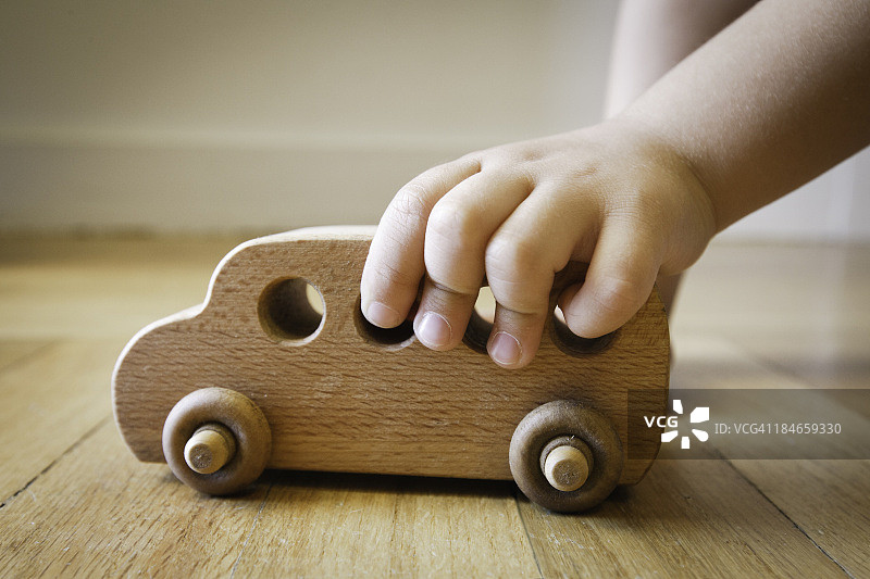 儿童在地板上玩木制玩具巴士图片素材