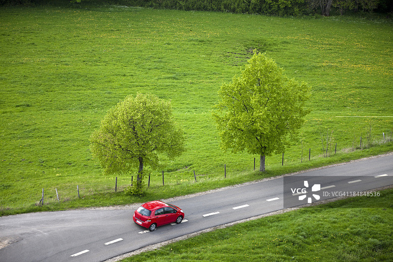 在乡村道路上行驶的红色小汽车图片素材