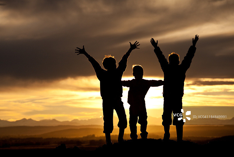 山区中三个快乐男孩的轮廓图片素材