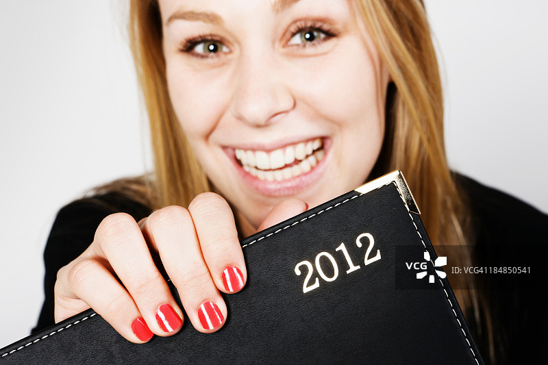 快乐自信的女商人对着2012年的日记微笑图片素材
