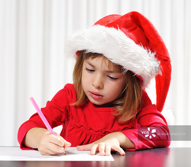 戴着圣诞帽的年轻女孩写便条图片素材
