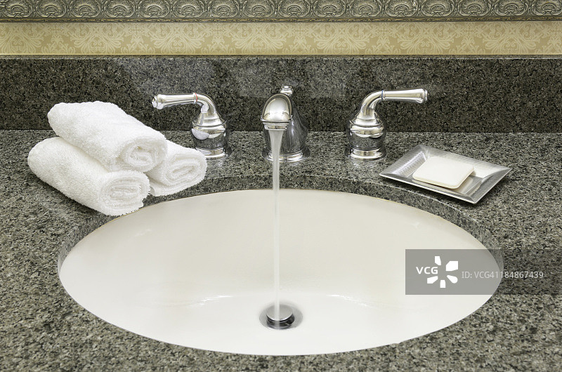 浴室水槽，从打开的水龙头流出的水图片素材