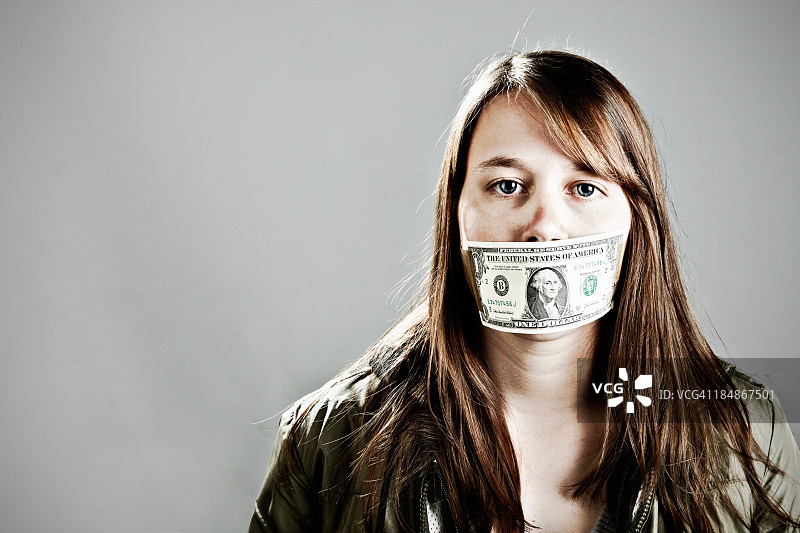 被美元堵住嘴的严肃年轻女子图片素材