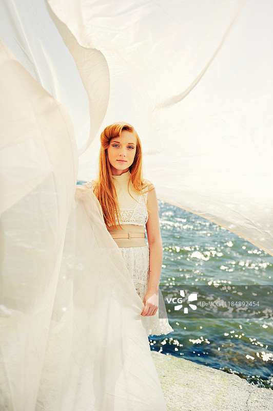 手持白色帆布的红发年轻女子肖像图片素材