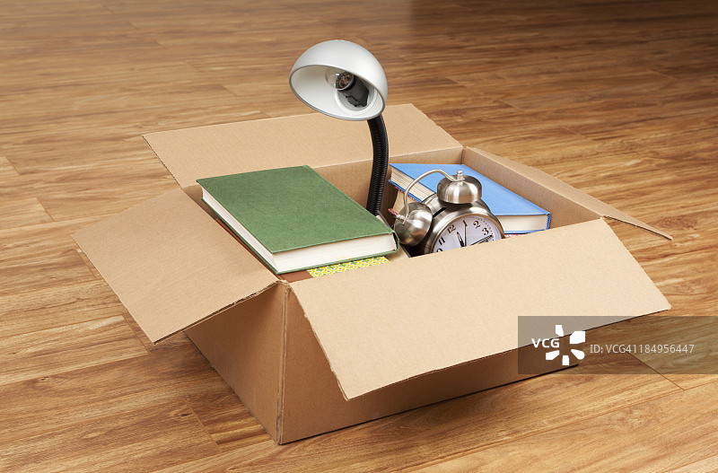 纸箱里的书籍、台灯和闹钟图片素材
