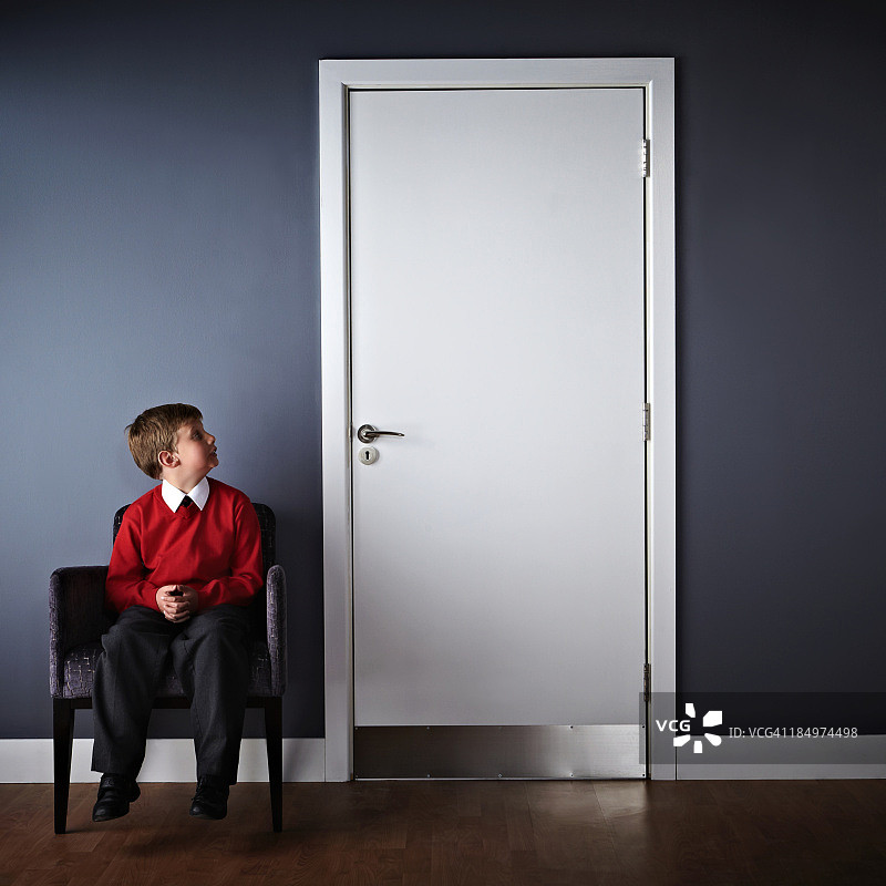 坐在校长办公室前的小男孩图片素材