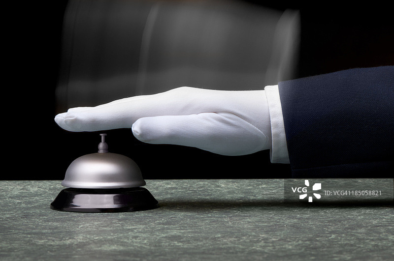 戴白色手套的手在柜台上按银色服务铃图片素材