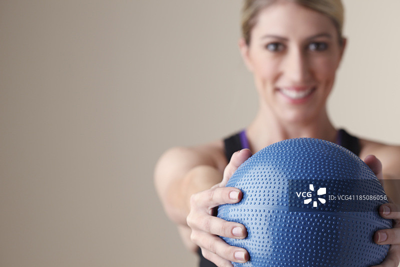 年轻女子伸展双臂，手持药球图片素材