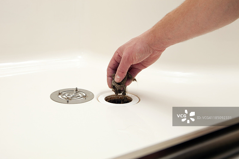 水管工清理淋浴排水口堵塞的毛发图片素材