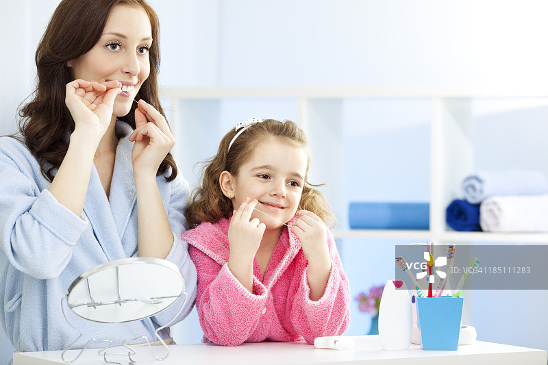 母亲和孩子一起用牙线清洁牙齿图片素材