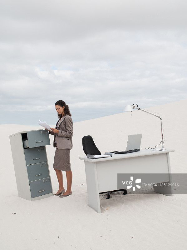 女商人站在沙漠中的文件柜旁图片素材