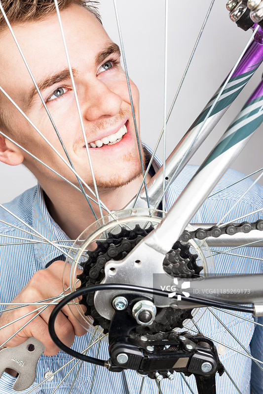 微笑的年轻男子维护他的自行车图片素材