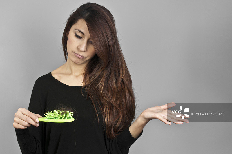 美女看着掉在梳子上的头发图片素材