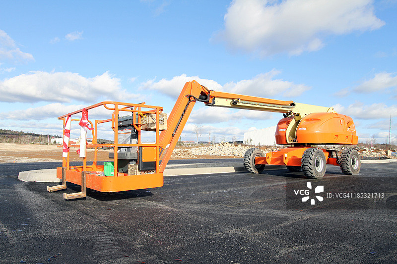 多云天空下的大型橙色高空作业平台图片素材