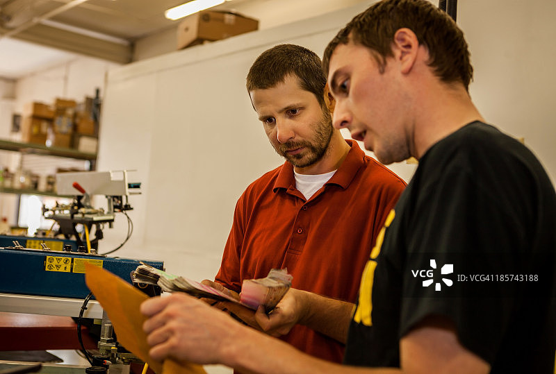 在丝网印刷车间查看色板的工人图片素材