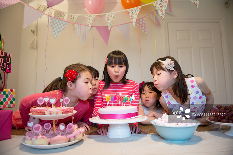 吹灭生日蛋糕蜡烛的女孩们图片素材