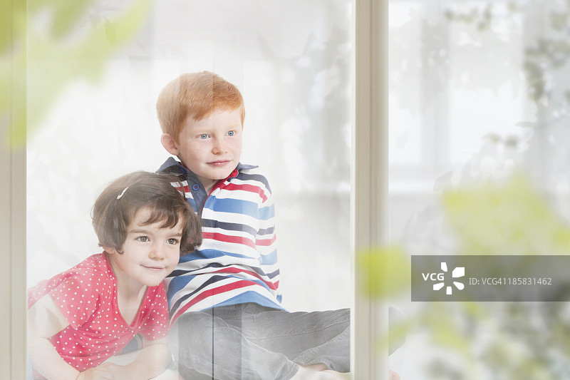 男孩和女孩坐在窗台上向外看图片素材