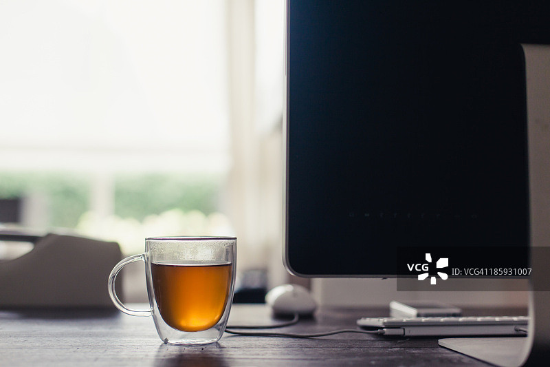 电脑旁的玻璃茶杯图片素材