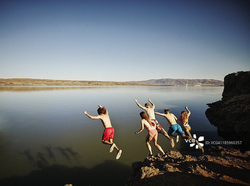 一群朋友从悬崖跳入河中图片素材
