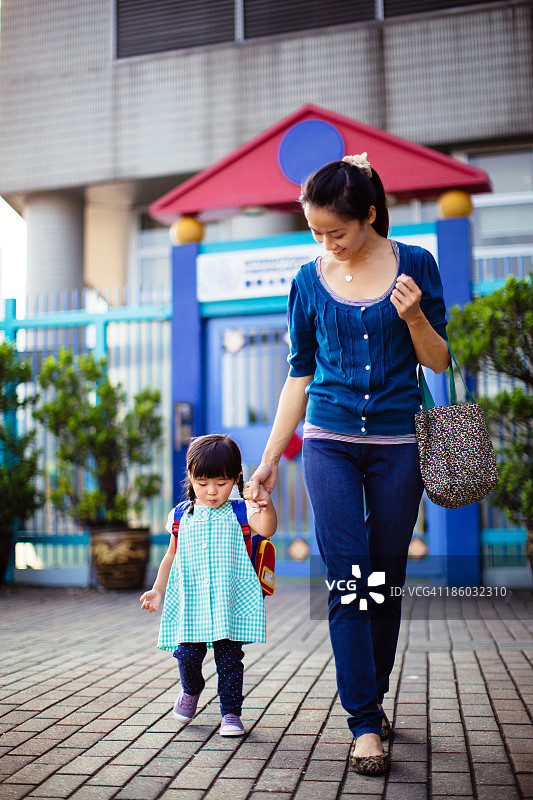 穿着制服的幼儿女孩牵着妈妈的手图片素材