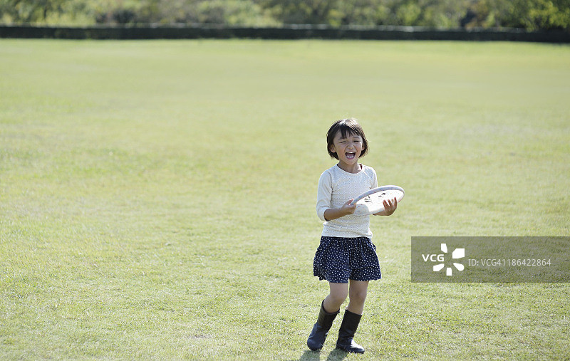 在绿地上玩飞盘的女孩图片素材