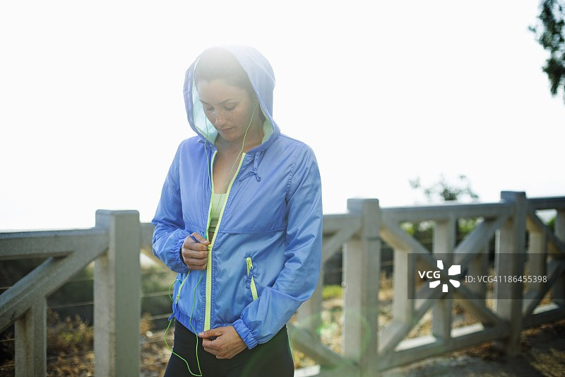 在长廊上拉起夹克的年轻金发女子图片素材