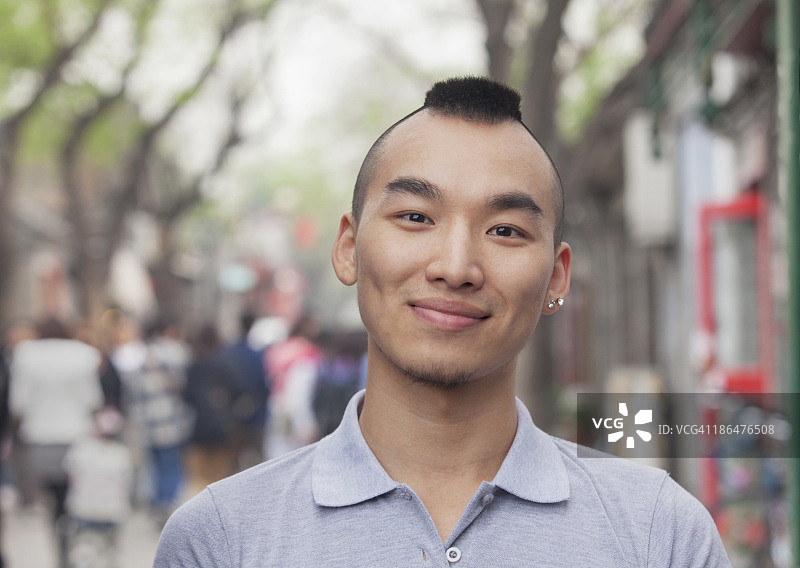 莫霍克发型的年轻男人对着镜头微笑图片素材