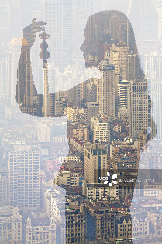 年轻女子手持中国风饰品与城市景观的双重曝光图片素材