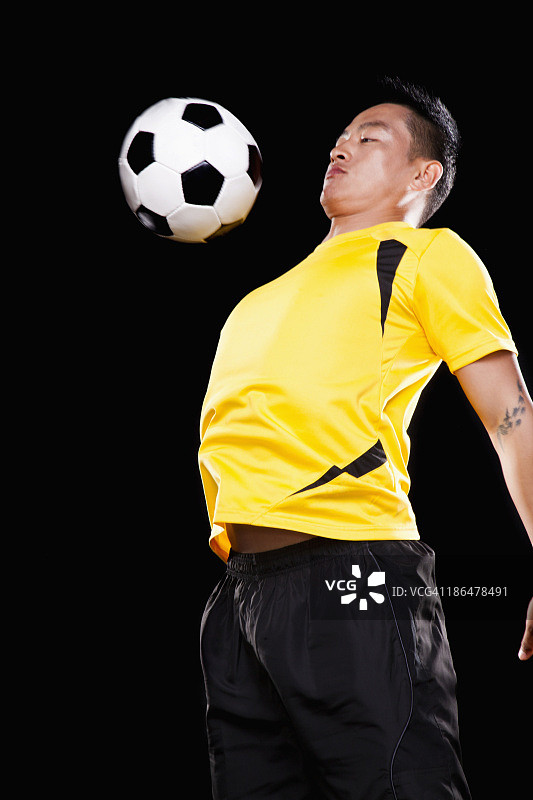 黑色背景的足球运动员胸部停球图片素材