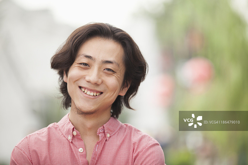 在中国北京南锣鼓巷的留长发微笑年轻男子图片素材