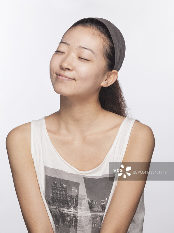 闭着眼睛的微笑年轻女人，工作室拍摄图片素材