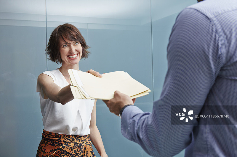 女人在办公室向男人递交文件图片素材