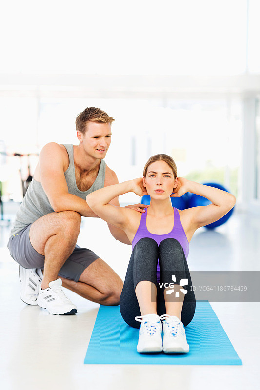 教练指导年轻女人做仰卧起坐图片素材