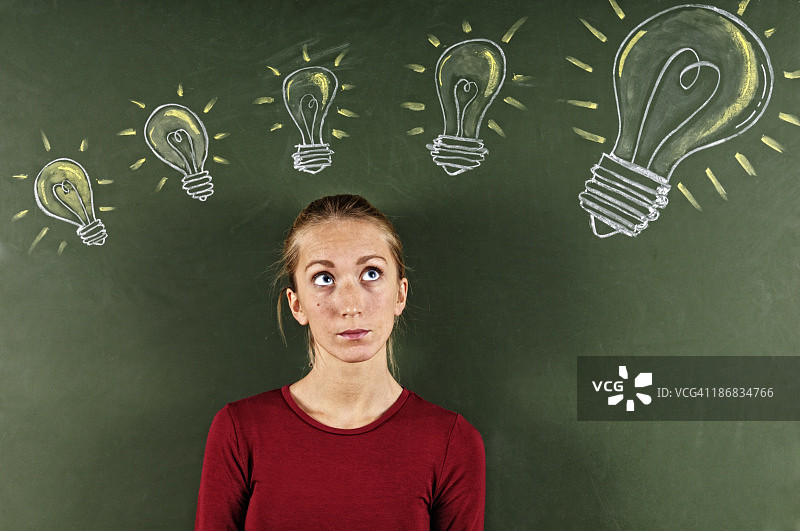 年轻女人看着素描的灯泡图片素材