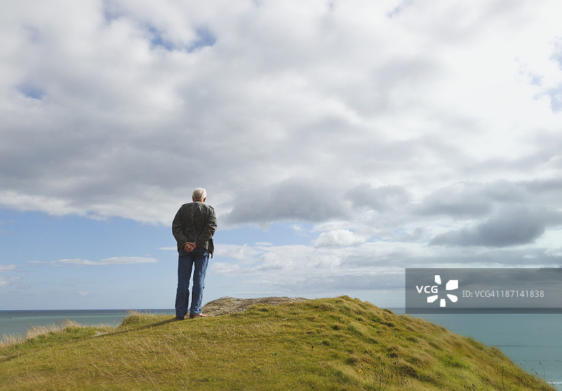 男人独自站在山丘上凝视着克洛纳基尔蒂附近的因奇多尼海滩图片素材