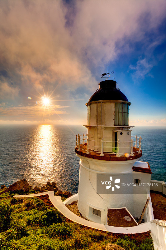日出时风暴海洋中岩石上的灯塔图片素材