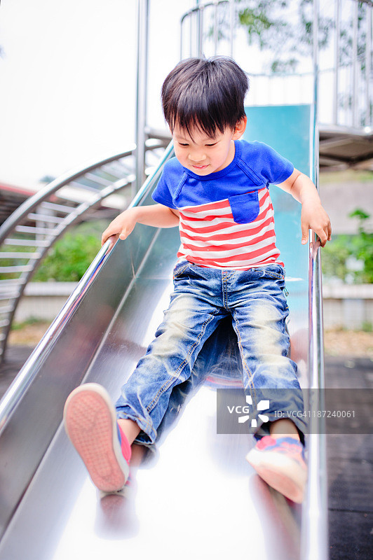 快乐的小男孩在玩滑梯图片素材