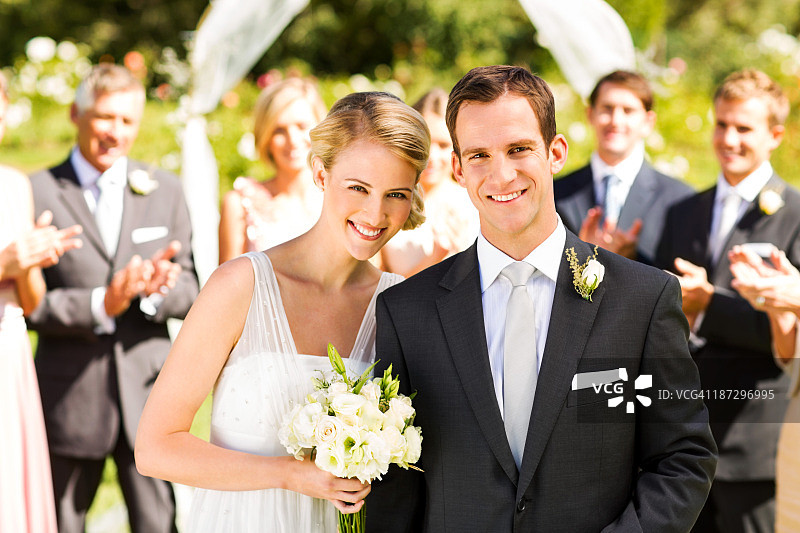 有宾客在背景中鼓掌的新婚夫妇图片素材