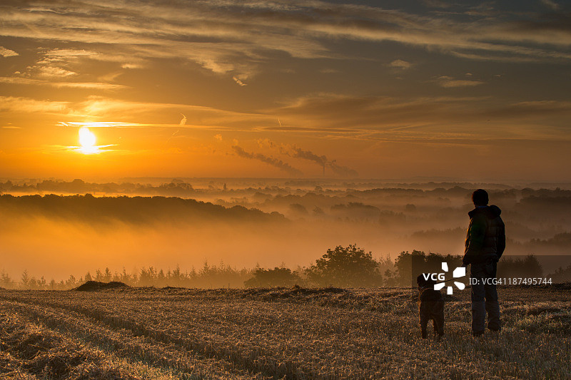 男人和狗享受薄雾日出图片素材