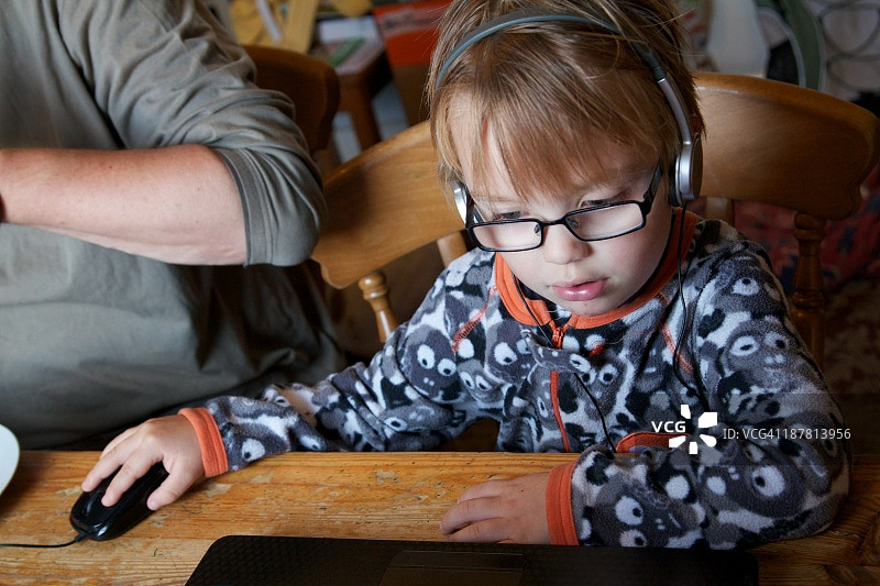 戴着耳机使用笔记本电脑的儿童图片素材