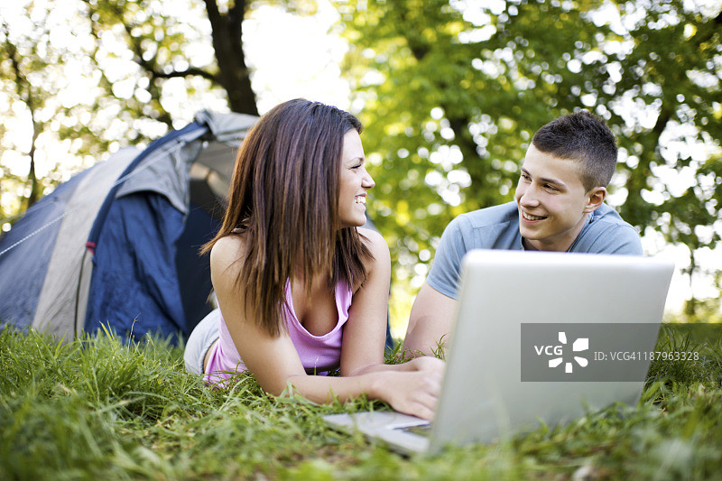 在户外使用笔记本电脑的青少年情侣图片素材