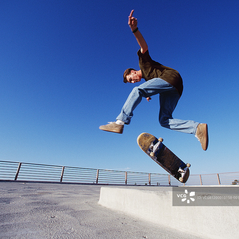 滑板公园里滑板运动员跳过路缘石（低角度）图片素材