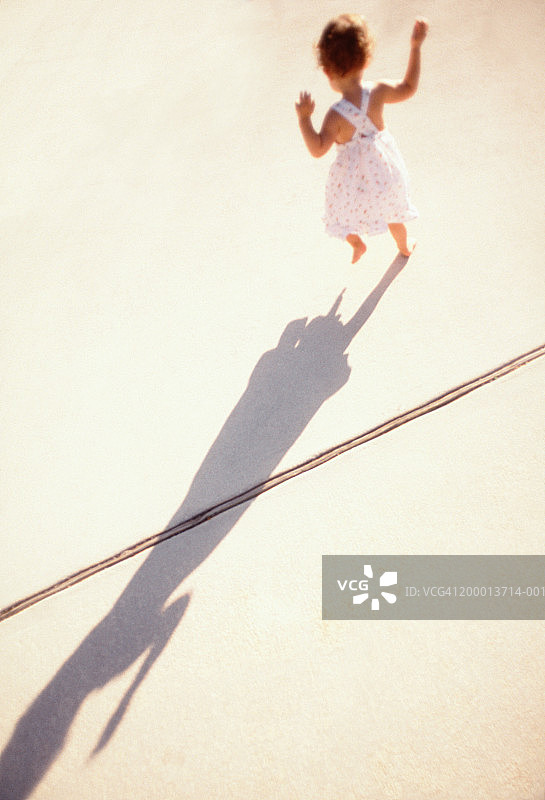 幼儿女孩在人行道上投下影子（后视图）图片素材