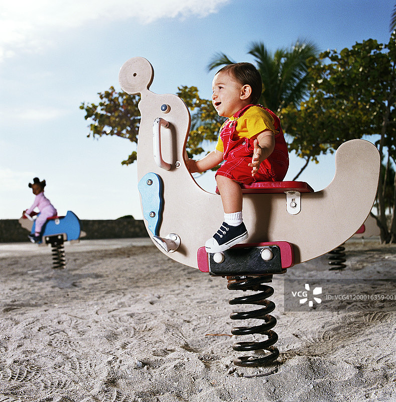 游乐场里的婴儿（12-15个月）（焦点在动物摇椅上的男孩）图片素材