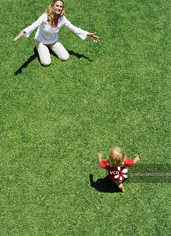 女童（18-21个月）在草坪上向母亲跑去图片素材
