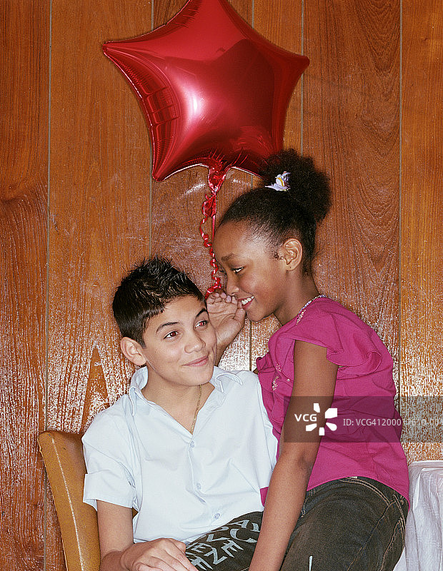 聚会上坐在男孩腿上的女孩（11-13岁）特写图片素材