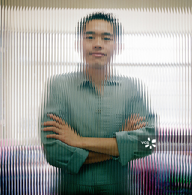 手臂交叉站在玻璃后的工人肖像图片素材