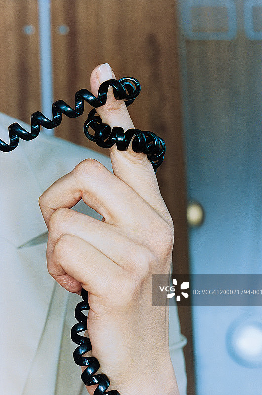 缠绕在女人手指上的电话线特写图片素材